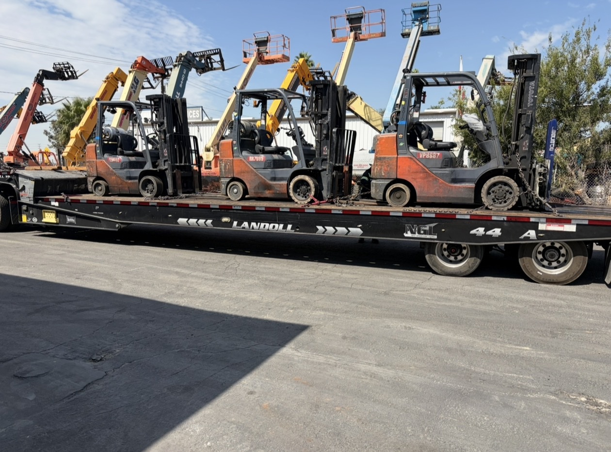 Toyota forklifts on a Landoll trailer with boom lifts in the background